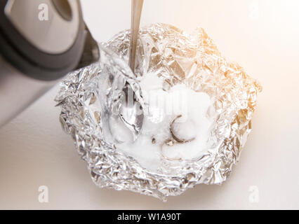 Eine Lösung aus Natron (Natriumbicarbonat) und warmem Wasser entfernen wird die Verfärbung von Silber, wenn das Silber ist in Kontakt mit einem Stück Alumini Stockfoto