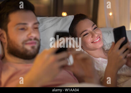 Paar mit Smartphones nachts im Bett Stockfoto