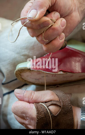 Schuster näht einen Schuh listig, mit Garn. Stockfoto