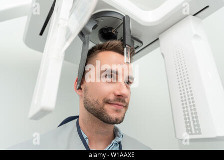 Schöner Mann stehenden Patienten in x-ray Machine. Panoramablick radiographie an professionelle zahnmedizinische Klinik. Stockfoto