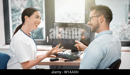 Zahnarzt und Patient die Wahl der Behandlung in einer Beratung mit x-ray Bild auf dem Bildschirm Stockfoto