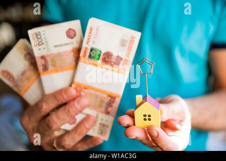 Steigende Preise für Wohneigentum. Der Mensch ist mit Geld in der Hand und House. Immobilien oder Immobilien investment. Geld, Haus. Immobilien Geld sparen für Wachstum. Stockfoto