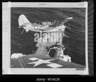 Eine Marine Curtiss SB2C Helldiver () ist vor dem Hintergrund der vorgesehenen aufgeschnappt, wie es von einem Streik bei Jap Liefer- Versandkosten. Weit unter anderen Ebenen werden auf dem Flugdeck, zu der die SB2C wird bald wieder entdeckt. Stockfoto