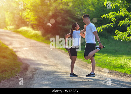 Junges Paar stretching Beine auf einer Straße am Park Stockfoto