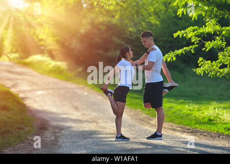 Junges Paar stretching Beine auf einer Straße am Park Stockfoto