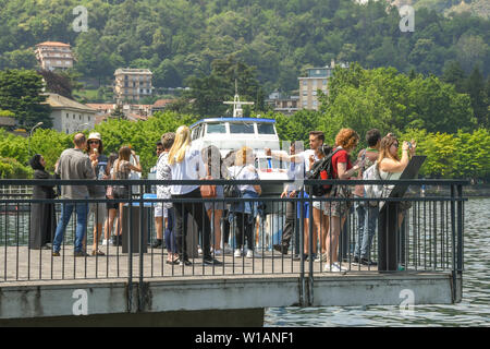 COMO, ITALIEN - JUNI 2019: Menschen auf der Seepromenade in Como auf einem Steg über die Wasser des Comer Sees. Stockfoto