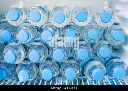 Reihen von vielen transparenten Plastikflaschen mit Trinkwasserversorgung im weißen Kühlschrank. Mineralwasser stapelbar im Kühlschrank zu trinken auf heiß Stockfoto