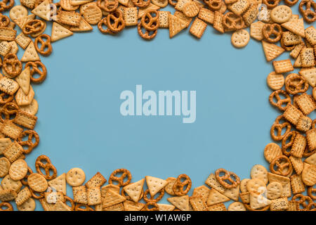 Rahmen einer Menge mini Cracker mit Mohn und Salzkristalle auf einem blauen Hintergrund, Flach, Ansicht von oben und kopieren. Stockfoto