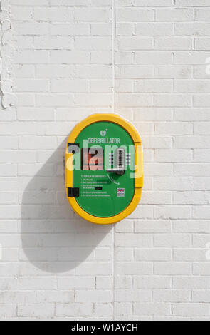 Lebensrettenden Defibrillator Ausrüstung auf Wand von Gebäude im Sport Bereich der lokalen Park Blackpool Lancashire England Großbritannien positioniert Stockfoto