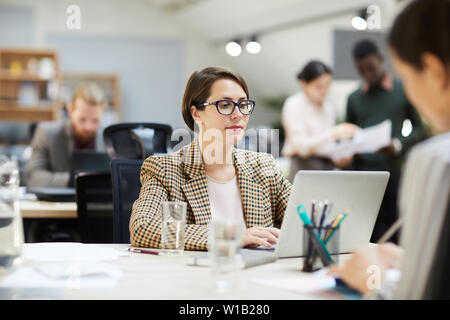 Portrait von professionellen Geschäftsfrau Brille mit Laptop, während am Schreibtisch im Büro arbeiten, kopieren Raum Stockfoto