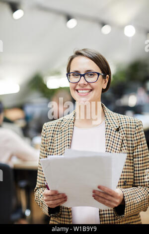 Taille bis Portrait von lächelnden Geschäftsfrau posiert in Amt, Dokumente Stockfoto