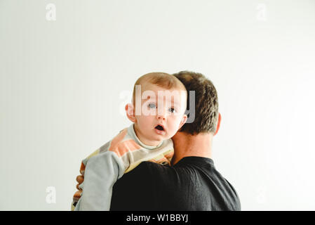 Baby in den Armen seines Vaters, auf weißem Hintergrund mit Kopie Raum isoliert. Stockfoto