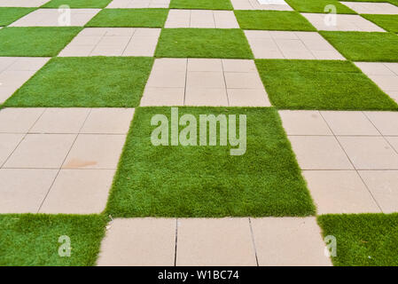 Der reale Hintergrund einige Fliesen mit Gras in Form von einem Schachbrett. Stockfoto