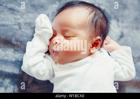 Closeup Portrait von cute adorable schlafen Asiatische Chinesische gemischten Rennen neugeborenes Mädchen Junge liegend auf Bett im Schlafzimmer. Gesunde glückliche Kindheit ethnischen Dive Stockfoto