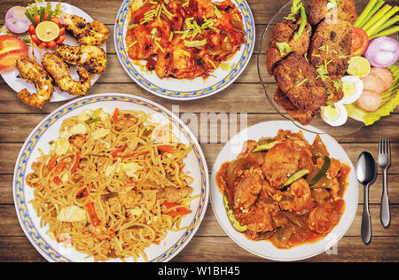 Leckeres indisches Essen Mahlzeit von Garnelen Nudeln mit scharfer Chili Huhn und red hot chili Fisch mit knusprigen Fisch, Pommes und frittierte Garnelen mit Salat serviert. Stockfoto