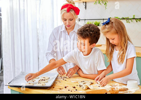 Blonde süße Mutter und Kinder machen Cookies in der Küche Stockfoto