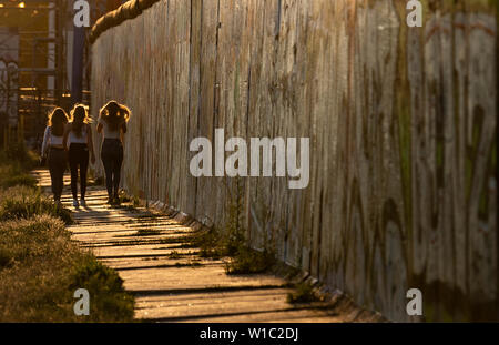 Berlin, Deutschland. 01. Juli, 2019. Drei Frauen sind bei einem Spaziergang an der East Side Gallery heute Abend. Credit: Paul Zinken/dpa/Alamy leben Nachrichten Stockfoto