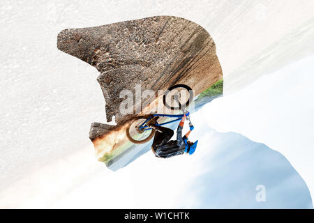 Doppelte Belichtung eines Mannes in Schutzhelm und Radprofi reiten auf die Berge. Konzept der Freeride- und off road Radfahren Stockfoto