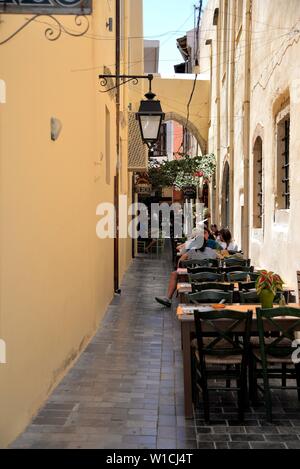 Die Menschen essen in einem Restaurant in einer malerischen Gasse der Altstadt von Rethymnon, Kreta, Griechenland. Stockfoto