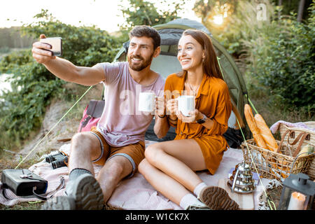 Junges Paar unter selfie Foto, Spaß beim Picknick in der Nähe der Hütte in den Wald Stockfoto