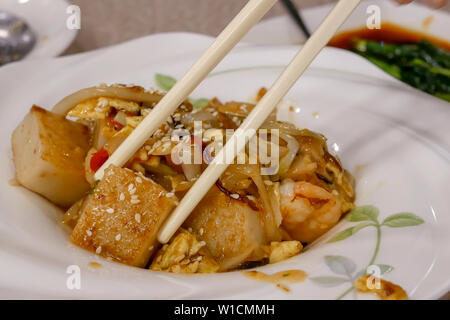 Bewegung von Menschen essen in der Pfanne gebratener Rübe Kuchen dim sum im Chinesischen Restaurant Stockfoto