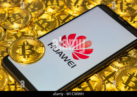 Gold Bitcoin Münzen Haufen mit dem Huawei Logo am Bildschirm des Smartphones. Stockfoto