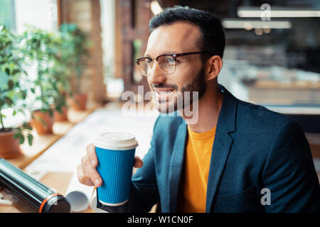 Kaffee bei der Arbeit. Stattlicher Mann mit dunklen Jacke Kaffee trinken bei der Arbeit vor dem Start Projekt Stockfoto