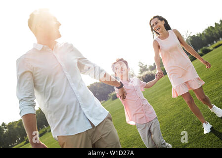 Schönen Tag mit der Familie. Volle Länge des kleinen, glücklichen jungen lächelnd und mit seinen Eltern in den Park. Familienkonzept Stockfoto