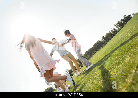 Spaß haben. Rückansicht der jungen Familie halten sich an den Händen und tanzen im Kreis und Zeit miteinander zu verbringen. Liebe und Familie Konzept Stockfoto