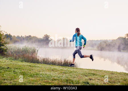 Frau läuft während nebeliger Morgen im City Park Stockfoto