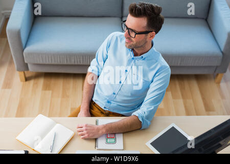 Glückliche Menschen wegschauen von Schreibtisch zu Hause sitzen Stockfoto