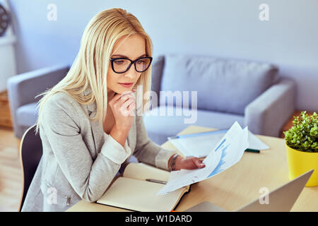 Junge Frau mit finanzieller Daten von Ihrem Home Office Stockfoto