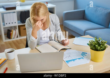 Betonte geschäftsfrau am Schreibtisch sitzen, arbeiten mit Laptop von home office Stockfoto
