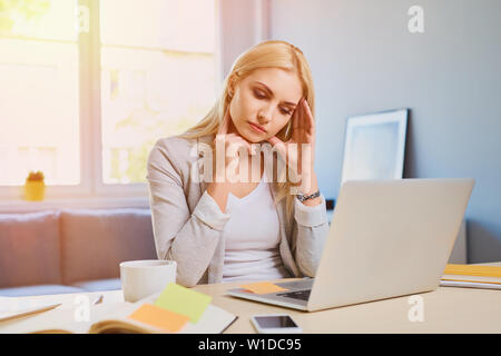 Junge Frau im Home Office leiden unter Kopfschmerzen. Stockfoto