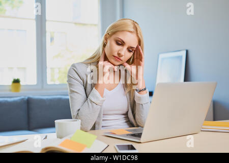 Junge Frau leidet unter Kopfschmerzen während der Arbeit im Home Office Stockfoto
