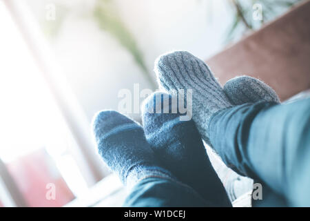 Füße mit wollsocken im Winter: Paar ist auf dem Sofa entspannen Stockfoto