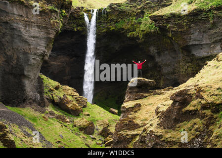 Kvernufoss Wasserfall in Island. Touristen in eine rote Jacke prüft Anblick Stockfoto