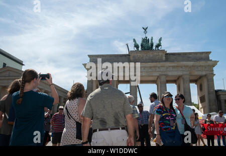 Berlin, Deutschland. 25. Juni 2019. Touristen stehen in der prallen Sonne vor dem Brandenburger Tor. Credit: Paul Zinken/dpa/Alamy leben Nachrichten Stockfoto