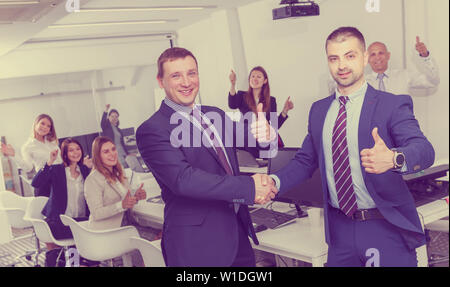 Zwei junge Unternehmer zufrieden die Hände schütteln, während Sie schlichten Treffen, die Vereinbarung Stockfoto