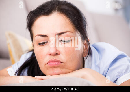 Junge traurige Frau liegend auf ein gemütliches Sofa und Melancholie zu Hause Stockfoto