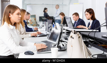 Junge angenehm fröhlichen positive Geschäftsfrau konzentrierte sich auf die Arbeit mit Laptop im Coworking Space Stockfoto