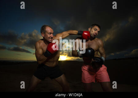 Starke Boxer tun Kickboxen Übung mit Trainer bei Sonnenuntergang Stockfoto