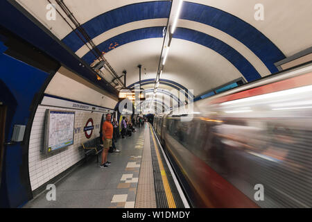 LONDON - 26. JUNI 2019: Personen und Zug auf der Plattform an der South Kensington U-Bahn Station in London Underground Stockfoto