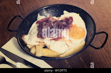 Gebrochene Spiegeleier mit Iberico Schinken und Bratkartoffeln Stockfoto