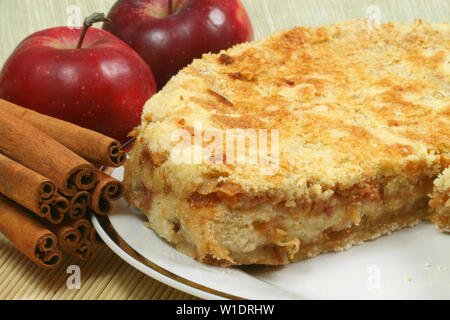 Frisch gebackenen Apfelkuchen mit roten Äpfeln und ganze Zimtstangen. Köstliches Dessert Stockfoto