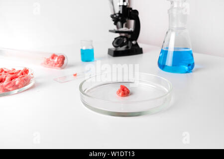 Künstliche Hackfleisch in Glas Petrischale für Laboruntersuchungen mit Mikroskop. Close Up. Chemischen Experiment. Stockfoto