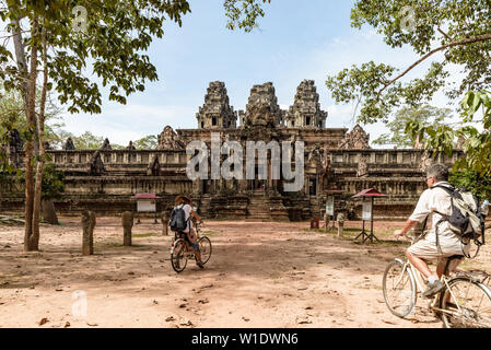 Touristische paar Radfahren rund um Tempel Angkor, Kambodscha. Ta Keo Gebäude Ruinen im Dschungel. Umweltfreundliche Tourismus Reisen, getönten Bild. Stockfoto