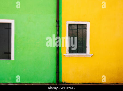 Blick auf den grünen und gelben Haus aus Stein und kleine weiße Fenster mit Fensterläden aus Holz. Minimalismus und freien Speicherplatz für Hintergrund Konzept. Stockfoto