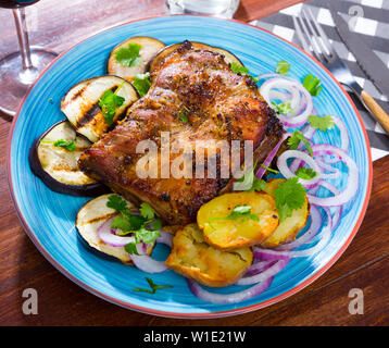 Gegrillte Schweinerippchen Rack garniert auf weiße Platte mit gebackenen Kartoffeln und Auberginen und Frische rote Zwiebel Stockfoto