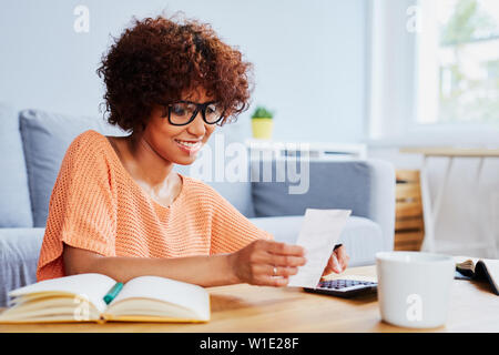 Glückliche junge Frau calcualte Home Finanzen Stockfoto